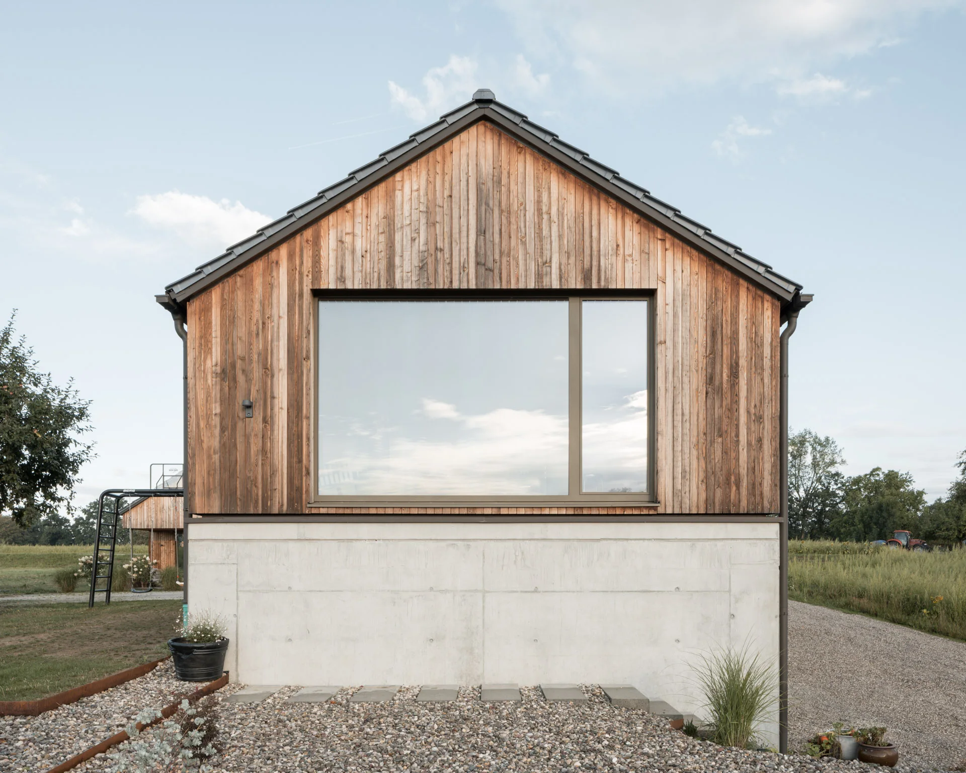 Giebelfassade mit großer Fensteröffnung auf Betonsockel