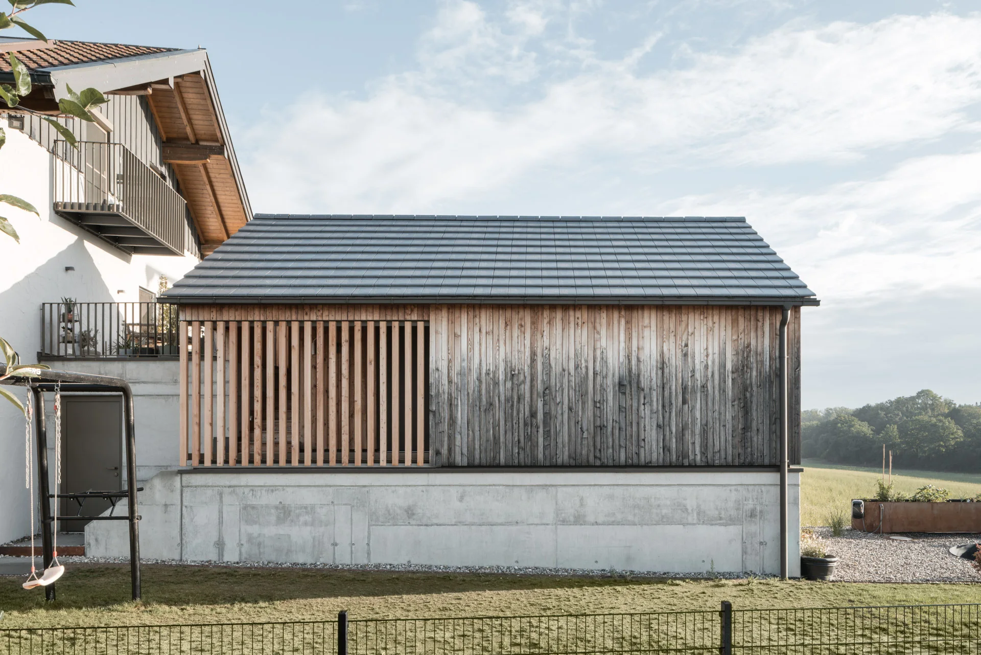 Holzfassade mit Lattung und Sockel aus Sichtbeton