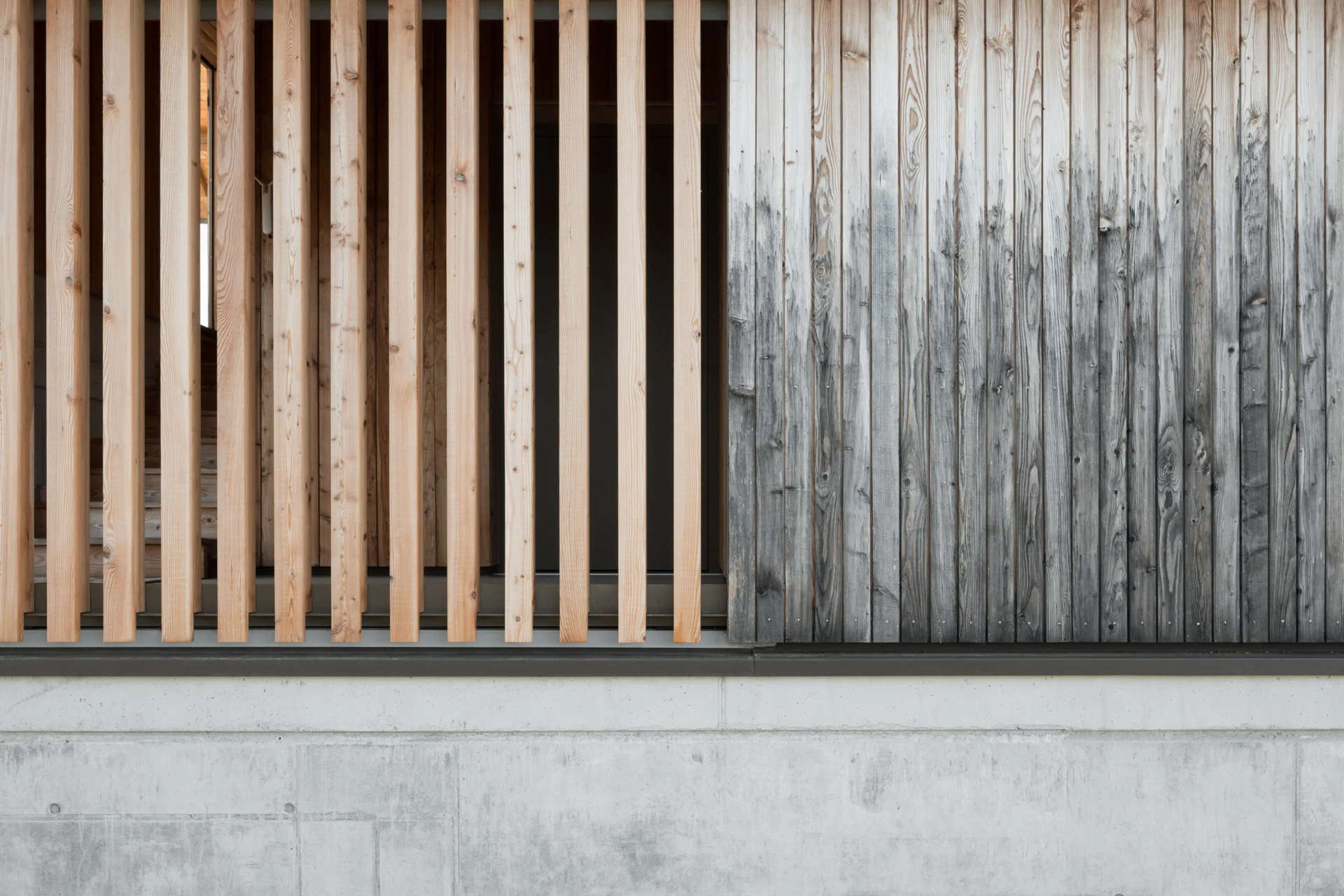 Detail der Fassade aus Holzlamellen und Sichtbeton